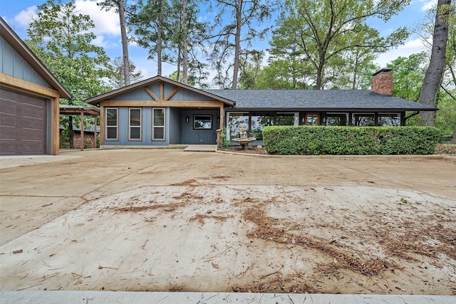 ranch-style home with a garage, driveway, a chimney, and a shingled roof