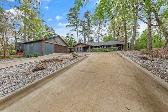 mid-century inspired home with concrete driveway, board and batten siding, and a chimney