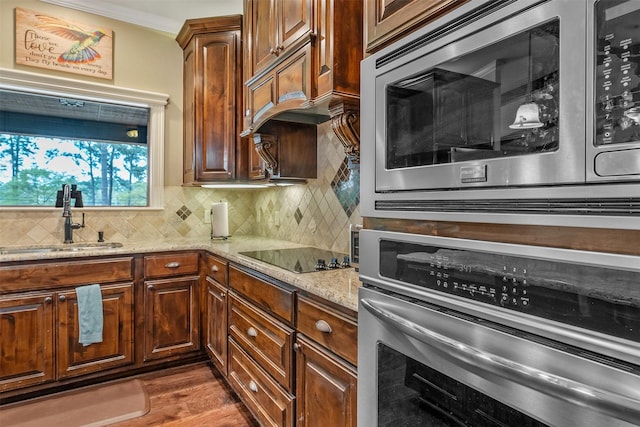 kitchen featuring light stone countertops, appliances with stainless steel finishes, a sink, backsplash, and dark wood-style floors