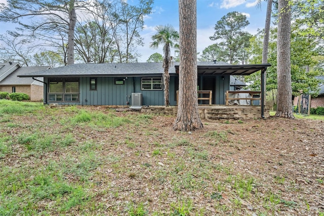 back of property with a shingled roof, board and batten siding, and cooling unit