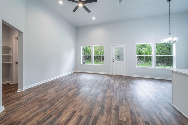 unfurnished living room with high vaulted ceiling, ceiling fan with notable chandelier, dark wood finished floors, and a wealth of natural light