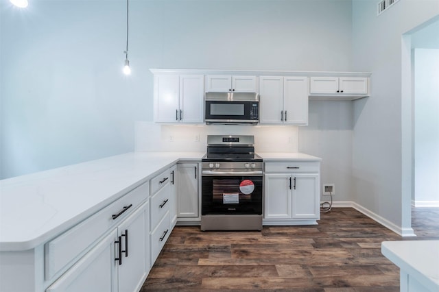 kitchen with appliances with stainless steel finishes, white cabinets, dark wood-type flooring, and visible vents