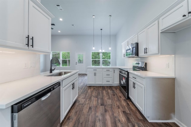 kitchen with dark wood-style flooring, a peninsula, white cabinetry, a sink, and stainless steel appliances