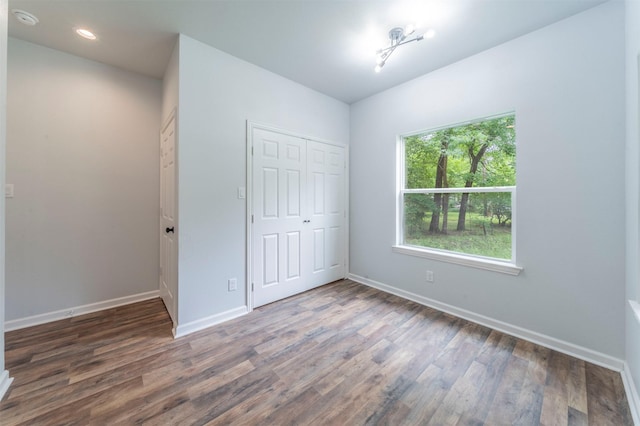 unfurnished bedroom featuring baseboards, wood finished floors, and a closet