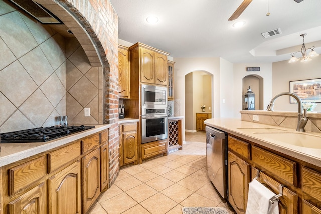 kitchen featuring visible vents, decorative backsplash, arched walkways, a sink, and stainless steel appliances