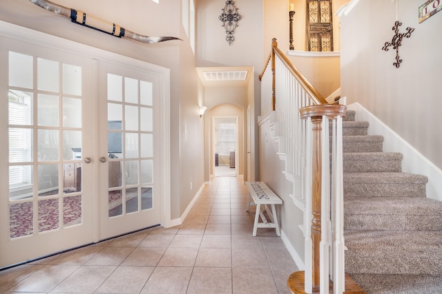 interior space with visible vents, baseboards, a high ceiling, stairway, and arched walkways