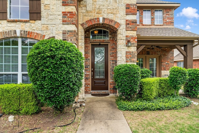 doorway to property with brick siding and roof with shingles