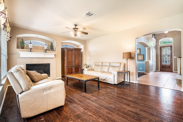 living room with a fireplace, arched walkways, hardwood / wood-style floors, a ceiling fan, and visible vents