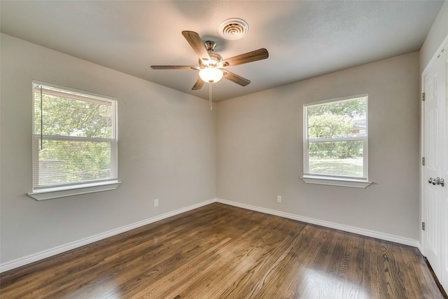 empty room with baseboards, plenty of natural light, a ceiling fan, and dark wood finished floors