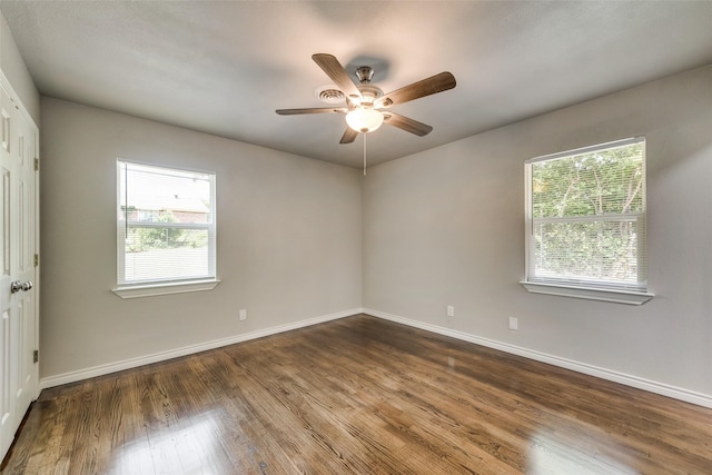 spare room with dark wood-type flooring, baseboards, ceiling fan, and a healthy amount of sunlight