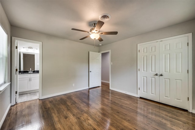 unfurnished bedroom featuring a closet, visible vents, dark wood-style flooring, baseboards, and ensuite bath