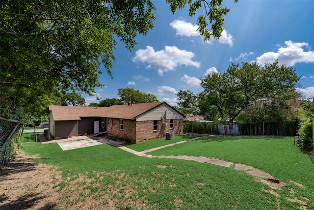 rear view of property with brick siding, a fenced backyard, a lawn, and a patio