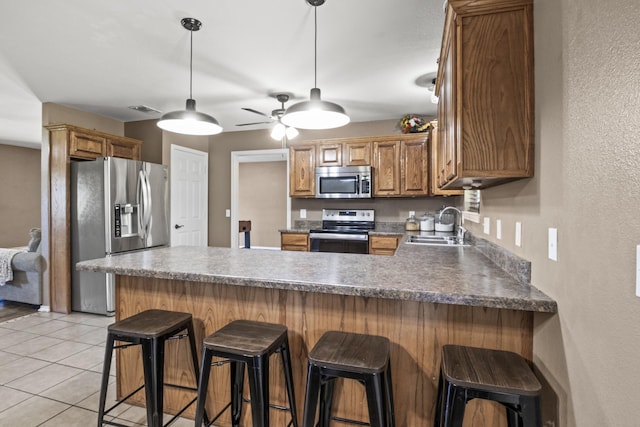 kitchen featuring visible vents, a peninsula, ceiling fan, a sink, and stainless steel appliances