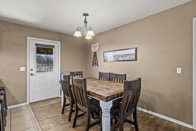 dining room with baseboards, wood finished floors, and a chandelier