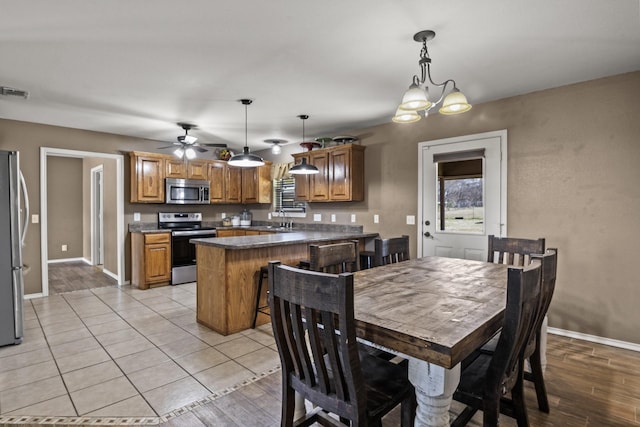 dining room with baseboards, light wood-style flooring, ceiling fan, and visible vents