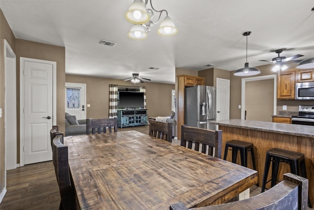 dining space with baseboards, ceiling fan with notable chandelier, dark wood-style flooring, and visible vents