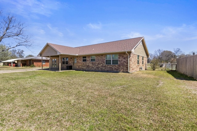 exterior space with fence, brick siding, concrete driveway, central air condition unit, and a yard