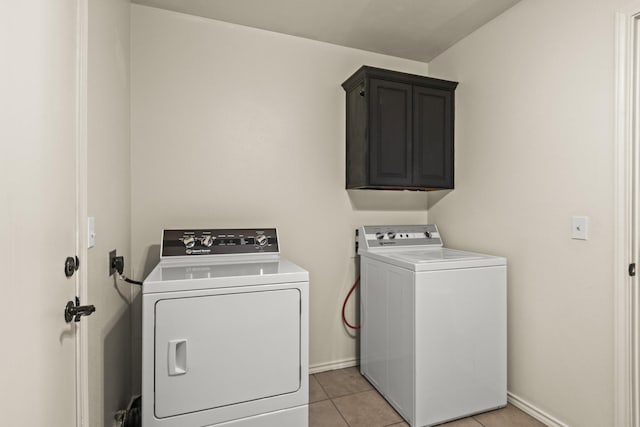 clothes washing area with light tile patterned floors, separate washer and dryer, baseboards, and cabinet space