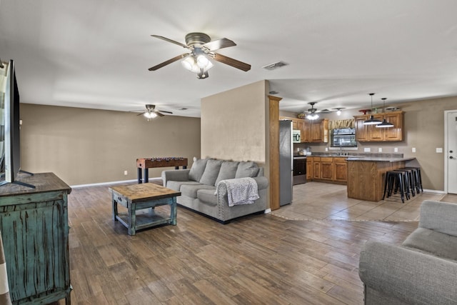 living area featuring visible vents, baseboards, ceiling fan, and wood finished floors