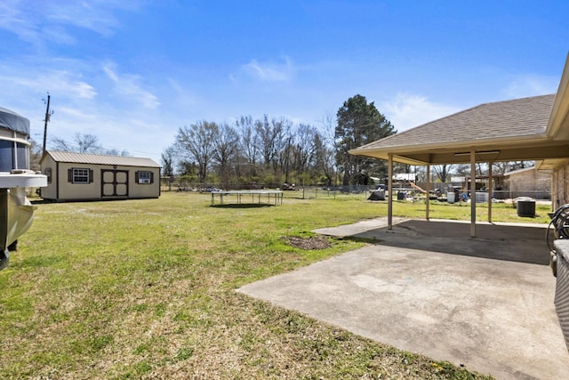 view of yard featuring an outdoor structure, a patio, a fenced backyard, a trampoline, and a carport