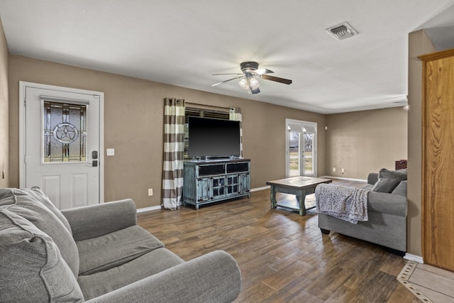 living area featuring visible vents, baseboards, ceiling fan, and wood finished floors