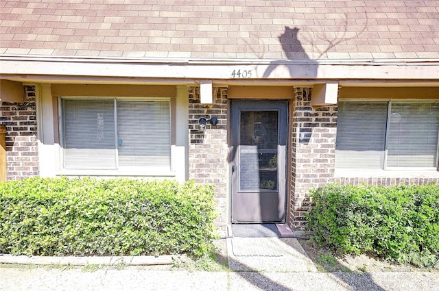 4405 Tophill Ln, Irving, TX 75038 - view of exterior entry with roof with shingles and brick siding