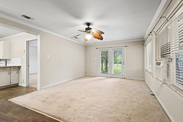 unfurnished living room with ceiling fan, light wood-style flooring, baseboards, visible vents, and ornamental molding