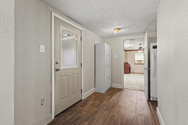 interior space with a textured ceiling, a textured wall, baseboards, and dark wood-type flooring