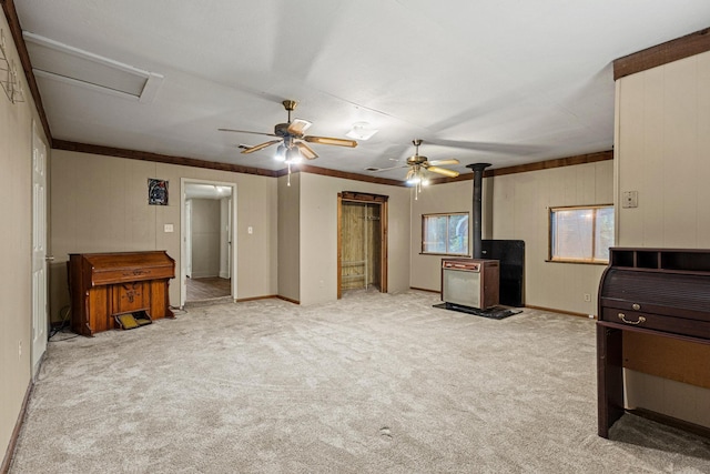 unfurnished living room with carpet floors, baseboards, a ceiling fan, and a wood stove
