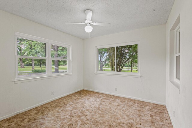 carpeted spare room featuring baseboards, a ceiling fan, and a textured ceiling