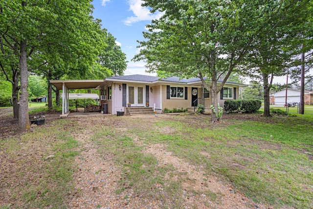 ranch-style house with dirt driveway, fence, a front yard, and an attached carport