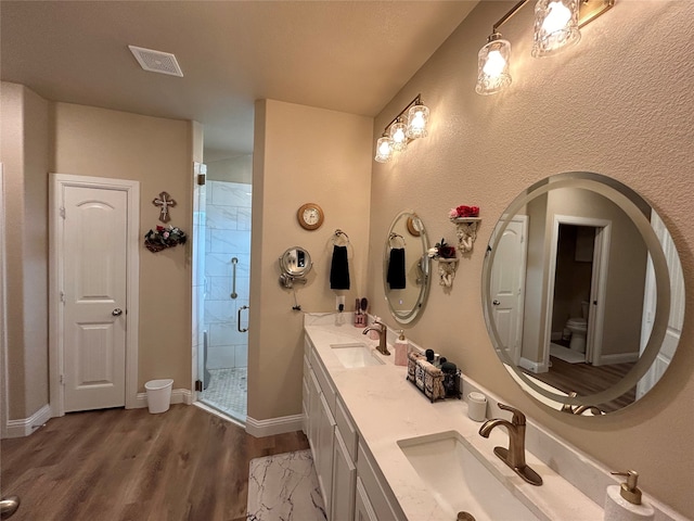 full bathroom featuring toilet, visible vents, a sink, and wood finished floors