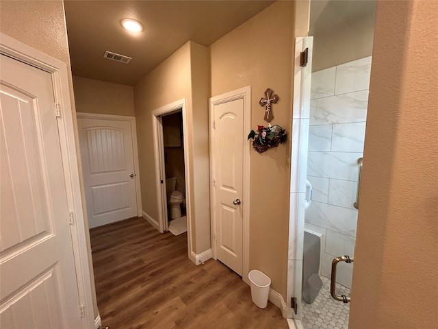 hall with baseboards, visible vents, and wood finished floors
