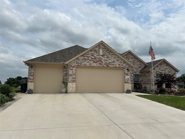 view of front of home featuring an attached garage, roof with shingles, driveway, and brick siding