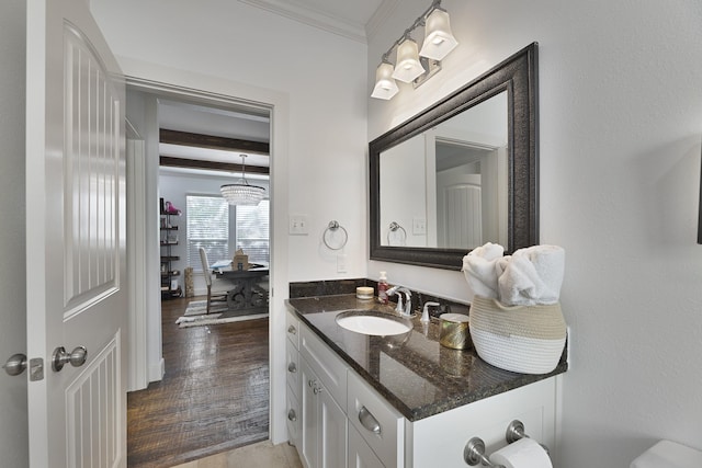 half bath featuring vanity, ornamental molding, beam ceiling, and wood finished floors