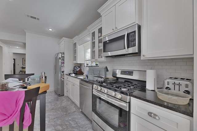 kitchen with appliances with stainless steel finishes, ornamental molding, backsplash, and white cabinets