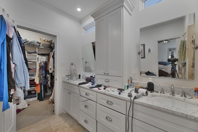 bathroom with crown molding, double vanity, ensuite bathroom, a spacious closet, and a sink