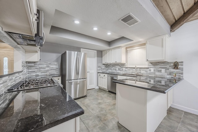 703 Athenia Way, Duncanville, TX 75137 - kitchen with stainless steel appliances, a sink, a peninsula, decorative backsplash, and white cabinets