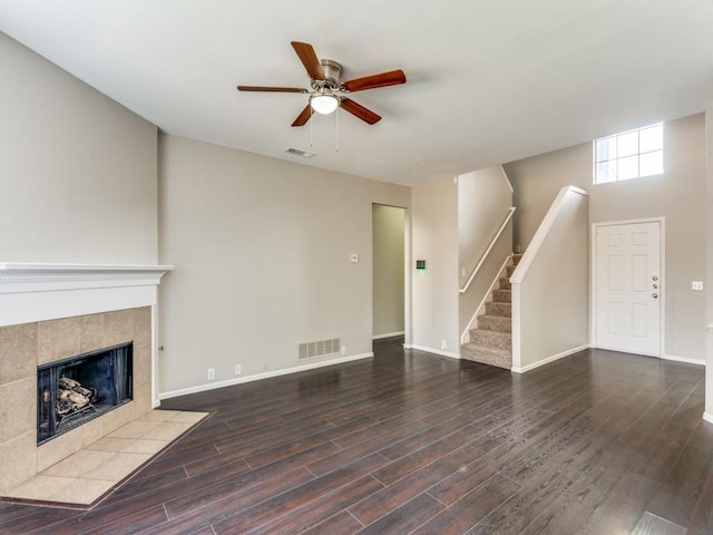unfurnished living room featuring ceiling fan, baseboards, wood finished floors, a tile fireplace, and visible vents