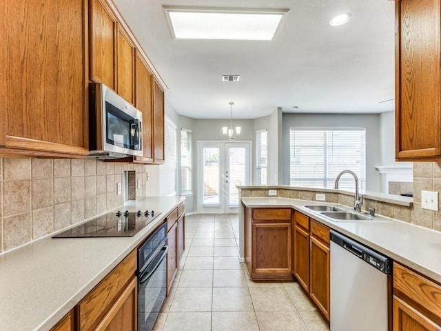 kitchen featuring light countertops, brown cabinets, a sink, backsplash, and black appliances
