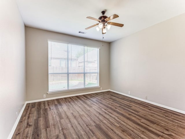 spare room featuring a ceiling fan, baseboards, visible vents, and wood finished floors