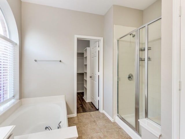 bathroom featuring a garden tub, a walk in closet, a stall shower, and a wealth of natural light