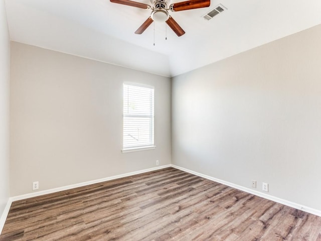 empty room featuring baseboards, visible vents, and wood finished floors