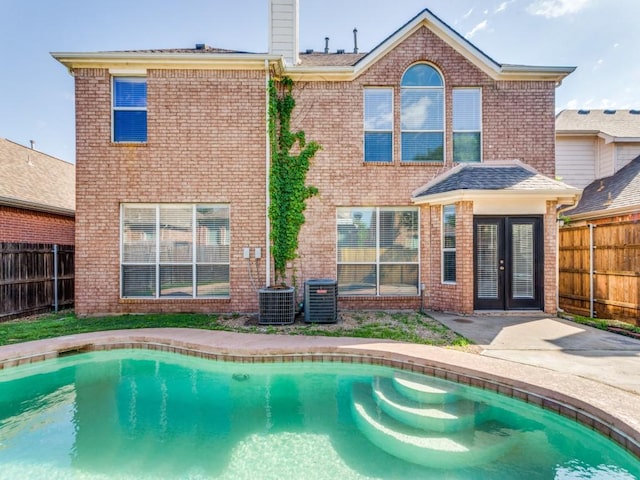 back of house with french doors, a fenced in pool, a fenced backyard, and brick siding