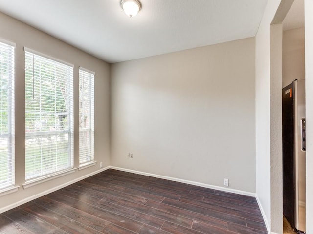 unfurnished room featuring baseboards and dark wood-style floors