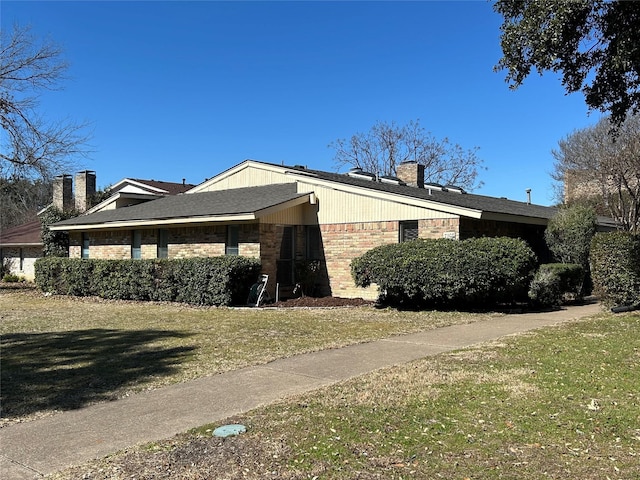 view of property exterior with a chimney, a yard, and brick siding