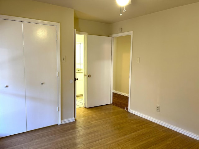 unfurnished bedroom featuring baseboards, a closet, and wood finished floors
