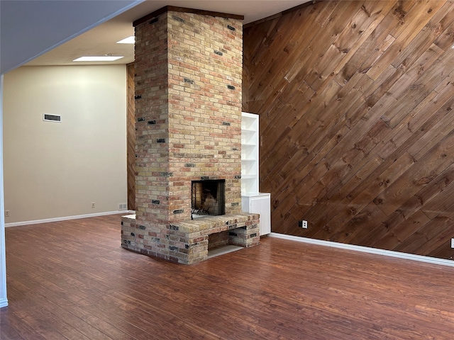 unfurnished living room featuring baseboards, wood walls, and wood finished floors