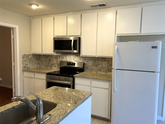 kitchen with visible vents, white cabinetry, tasteful backsplash, a sink, and stainless steel appliances