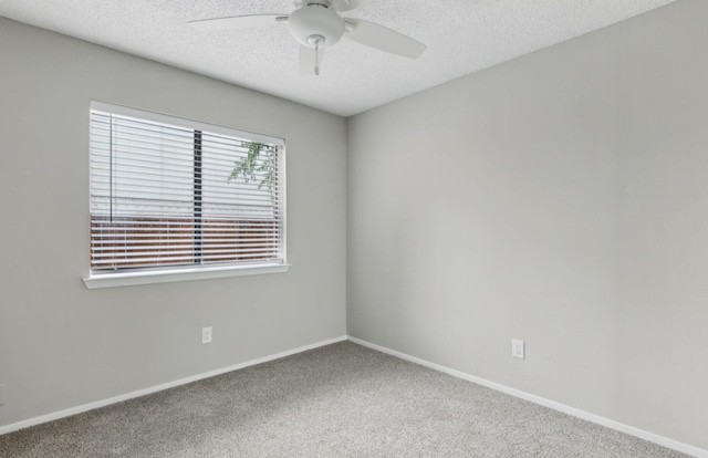 carpeted spare room featuring a textured ceiling, baseboards, and ceiling fan